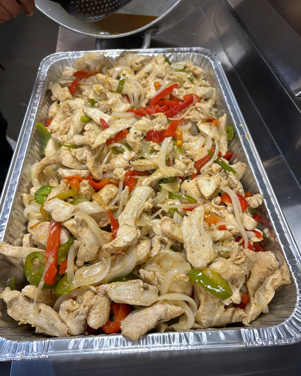 Fresh chicken fajita with peppers and onions in a full catering tray