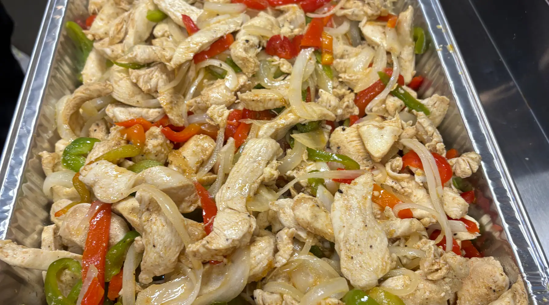 Chicken fajita with peppers and onions in a full catering tray